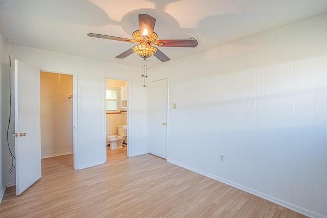 unfurnished bedroom with ceiling fan, ensuite bath, and light wood-style floors