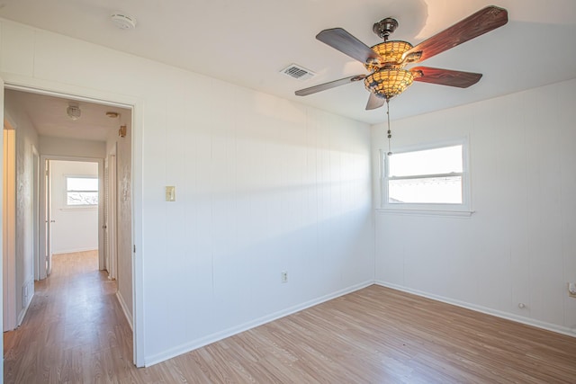 unfurnished room with light wood-type flooring, visible vents, ceiling fan, and baseboards