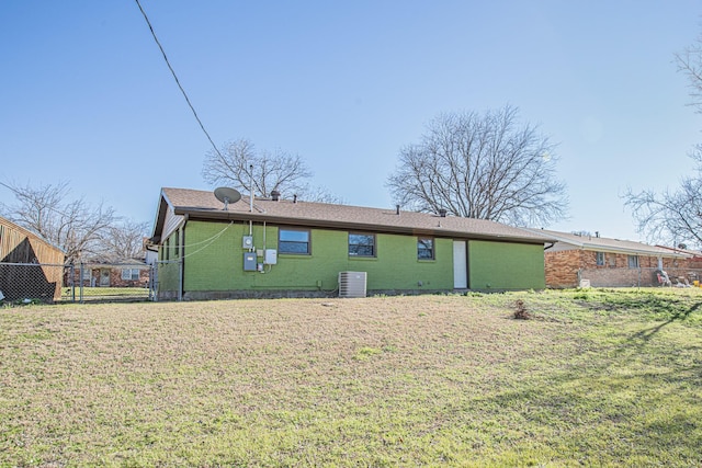 back of house featuring central AC unit, a yard, fence, and brick siding