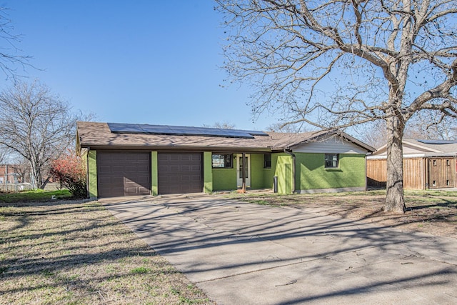 view of front of house with an attached garage, brick siding, fence, concrete driveway, and roof mounted solar panels