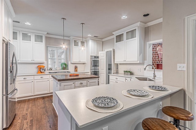 kitchen with visible vents, a peninsula, stainless steel appliances, crown molding, and a sink