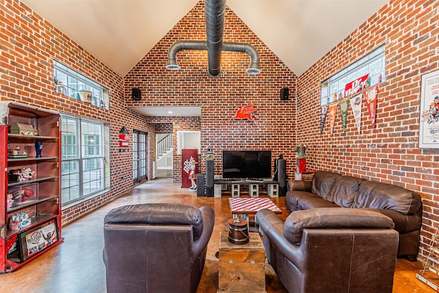 living area featuring high vaulted ceiling, concrete flooring, stairway, and brick wall