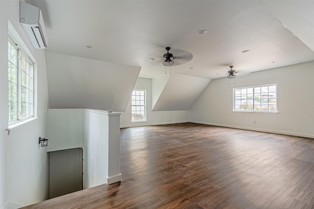 bonus room featuring ceiling fan, wood finished floors, baseboards, vaulted ceiling, and a wall mounted AC