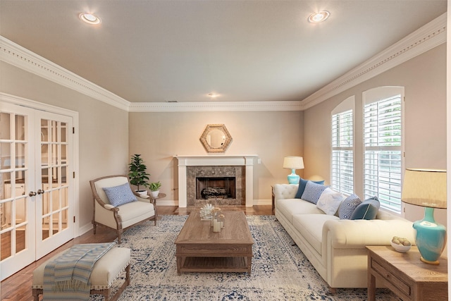 living room with french doors, a fireplace, wood finished floors, and crown molding