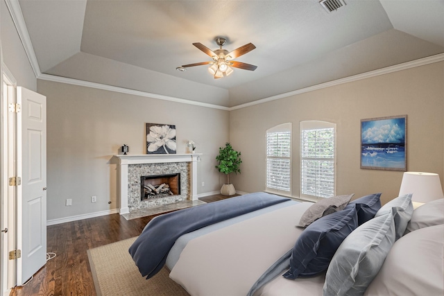 bedroom featuring dark wood-style floors, a raised ceiling, visible vents, a premium fireplace, and baseboards