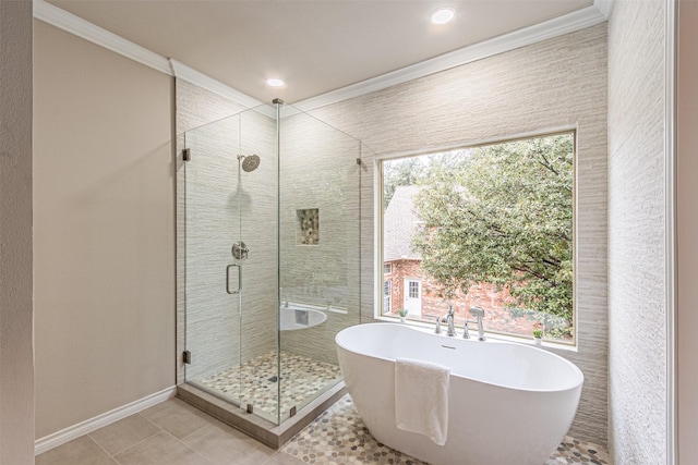 full bath with crown molding, a stall shower, tile patterned flooring, a freestanding tub, and baseboards