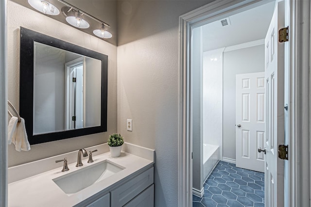 full bathroom with visible vents, a textured wall, tile patterned flooring, vanity, and a bath