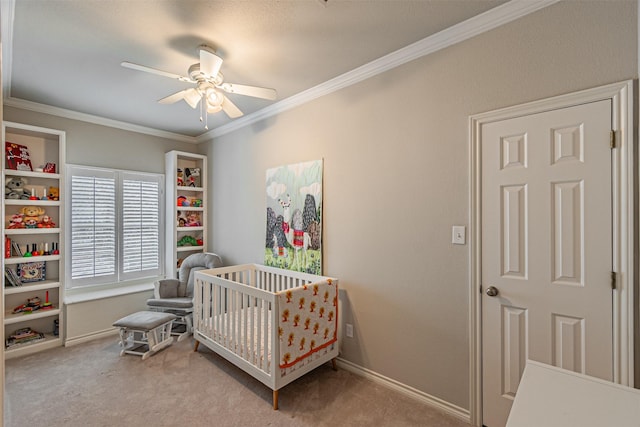 carpeted bedroom featuring ornamental molding, a crib, a ceiling fan, and baseboards