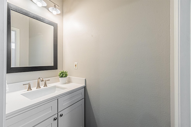 bathroom with a textured wall and vanity