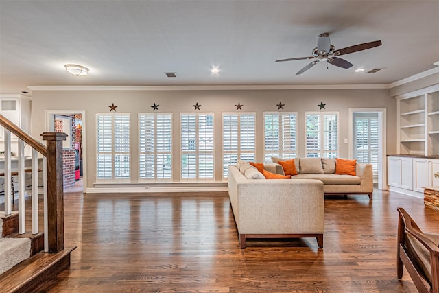 living area with built in shelves, dark wood-style flooring, a wealth of natural light, and crown molding