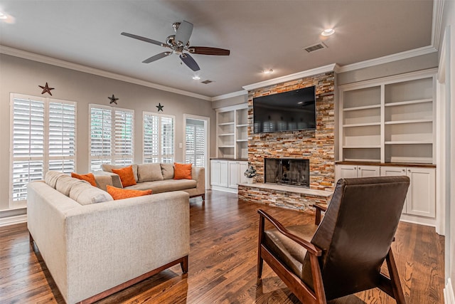 living room with crown molding, visible vents, dark wood-type flooring, ceiling fan, and a stone fireplace