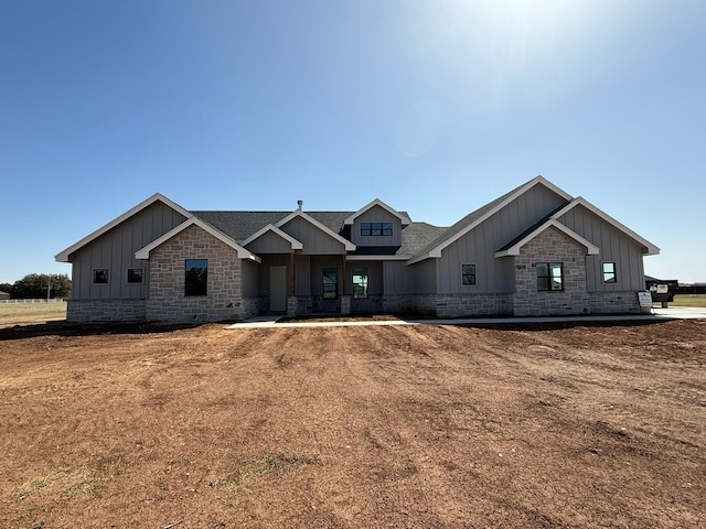 craftsman house with board and batten siding, stone siding, and roof with shingles