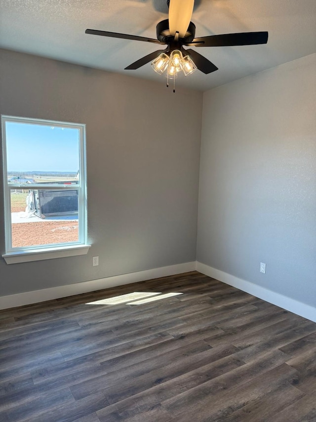 empty room featuring a textured ceiling, dark wood finished floors, a ceiling fan, and baseboards