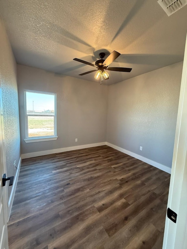 empty room with dark wood-style floors, baseboards, visible vents, and a textured ceiling