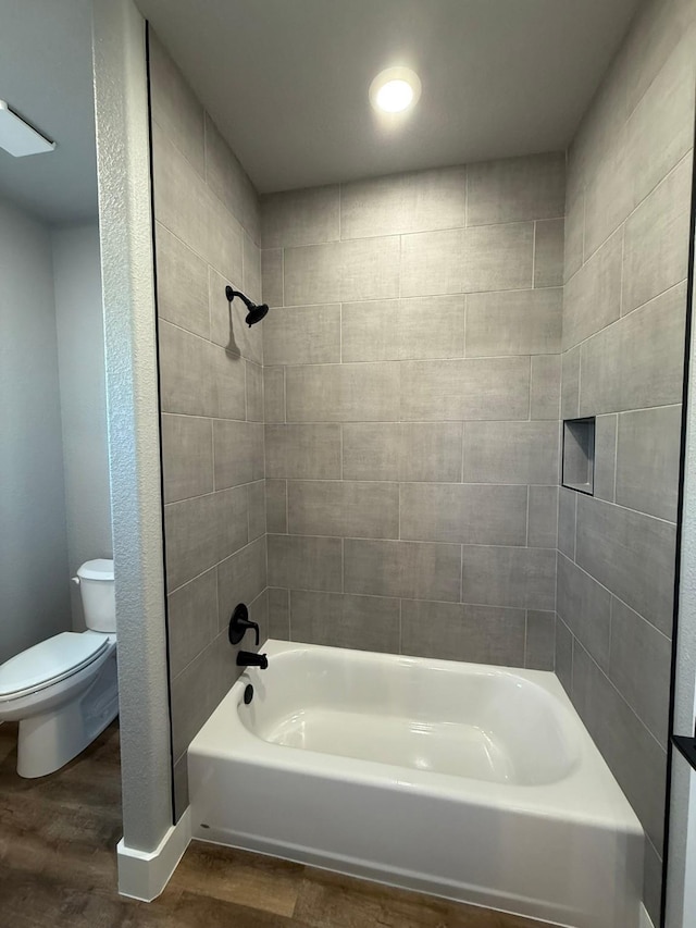 full bath featuring shower / washtub combination, toilet, and wood finished floors