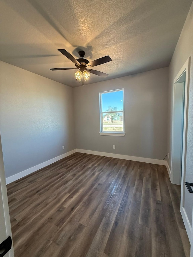 spare room featuring baseboards, dark wood finished floors, and a textured ceiling