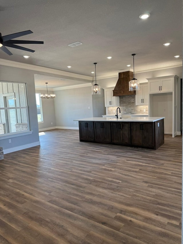 kitchen with premium range hood, crown molding, white cabinetry, and a sink