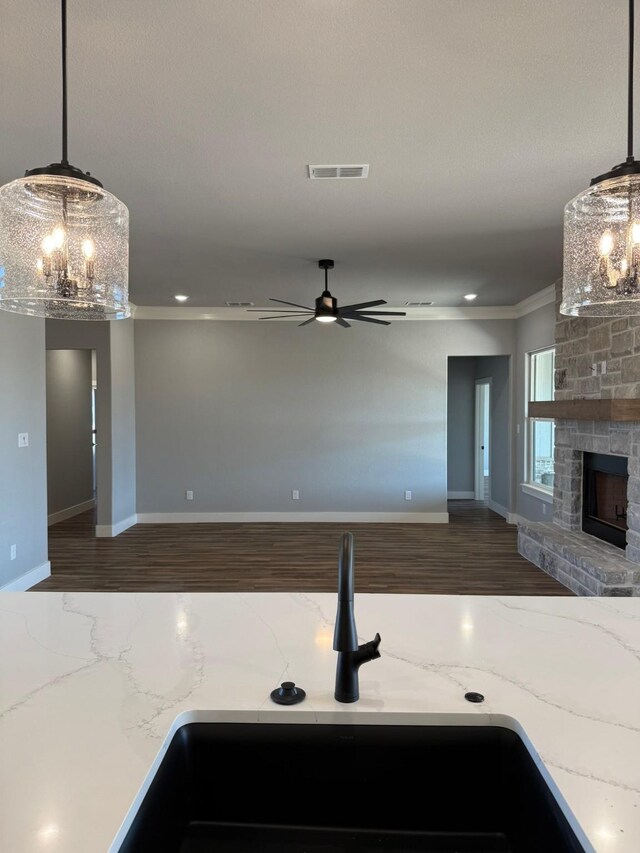 kitchen with light stone countertops, visible vents, open floor plan, a stone fireplace, and wood finished floors