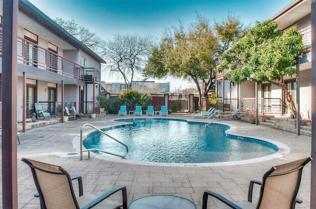 community pool with a patio and fence