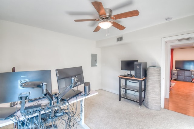 carpeted home office with ceiling fan, electric panel, and visible vents