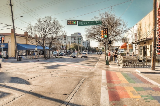 view of road featuring sidewalks, traffic lights, street lighting, and curbs