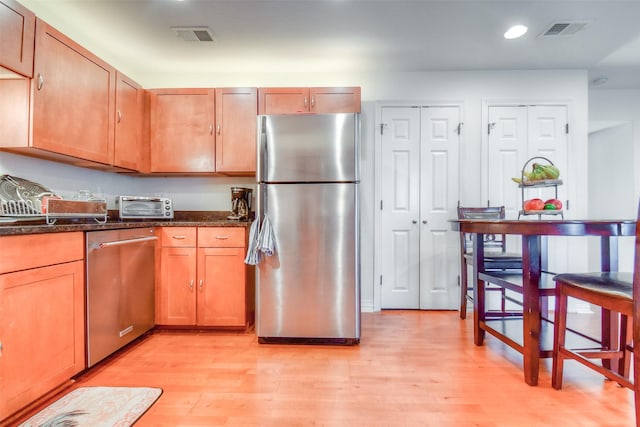 kitchen with a toaster, light wood finished floors, visible vents, and appliances with stainless steel finishes