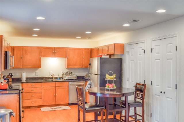 kitchen with visible vents, appliances with stainless steel finishes, brown cabinets, a sink, and recessed lighting