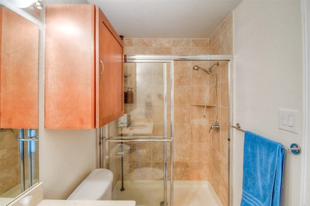 bathroom with a textured ceiling, a textured wall, a stall shower, and toilet