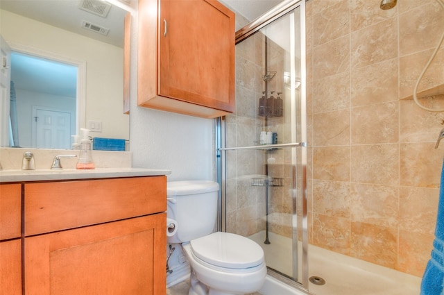 bathroom featuring visible vents, toilet, a shower stall, and vanity