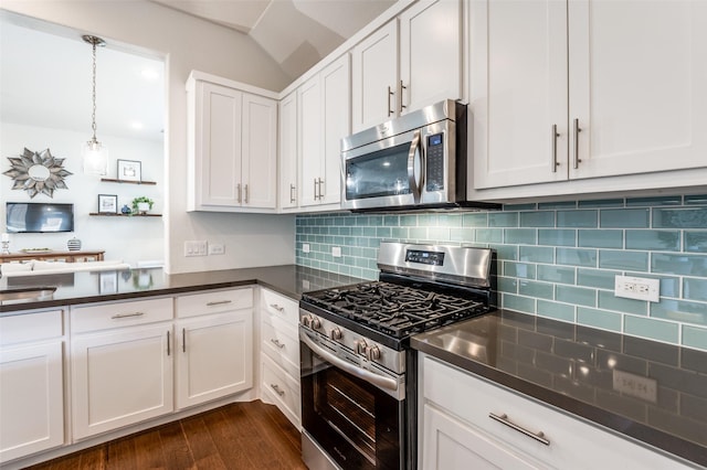 kitchen with stainless steel appliances, white cabinetry, backsplash, dark wood-style floors, and dark countertops