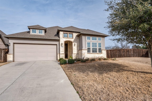 view of front facade featuring an attached garage, fence, driveway, stone siding, and stucco siding