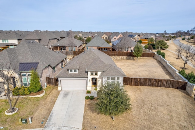 view of front facade featuring a residential view, concrete driveway, roof with shingles, and fence