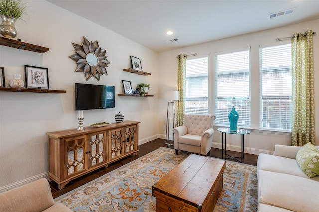 living area featuring dark wood-type flooring, visible vents, and baseboards