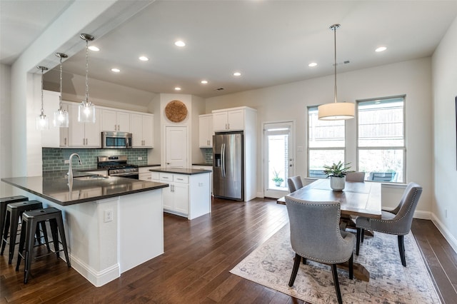 kitchen with tasteful backsplash, dark countertops, dark wood-type flooring, stainless steel appliances, and a sink