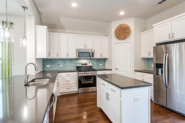 kitchen with dark countertops, appliances with stainless steel finishes, dark wood-style flooring, and a sink