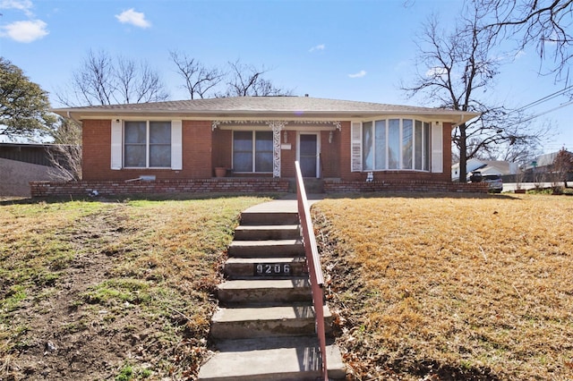 view of front facade with brick siding and a front lawn