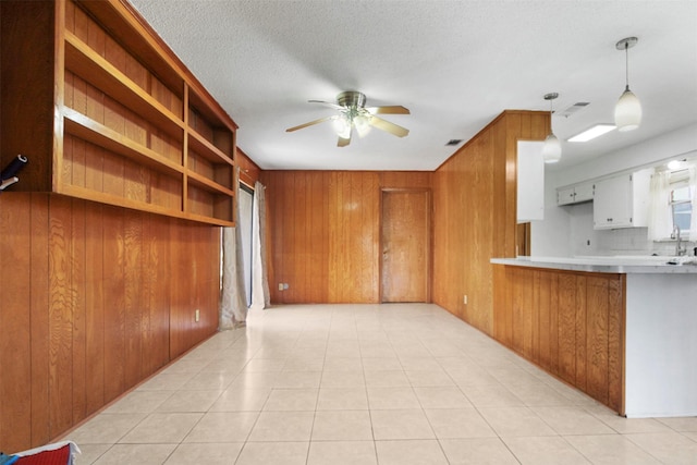 kitchen with wood walls, visible vents, a ceiling fan, light countertops, and tasteful backsplash