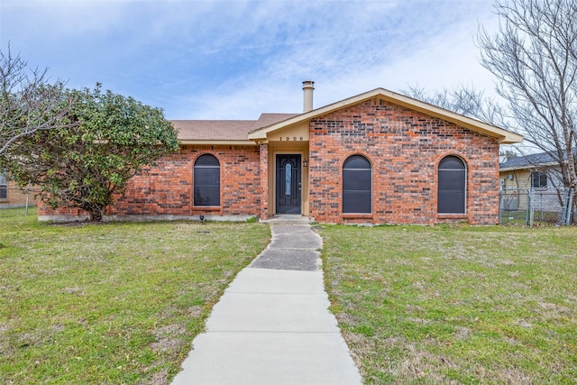 ranch-style home featuring a front yard, brick siding, and fence