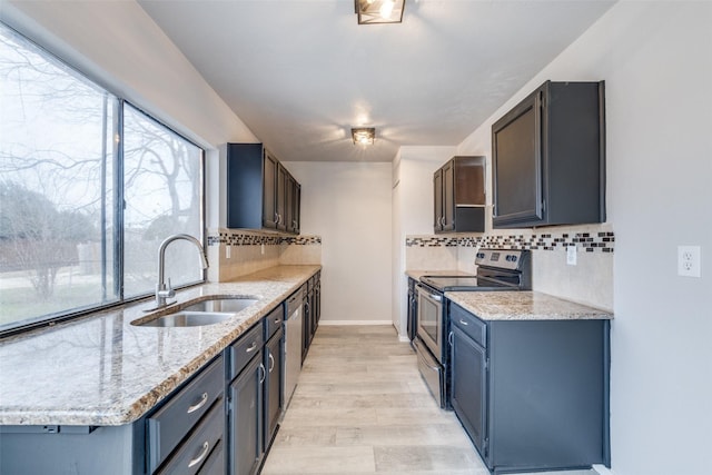 kitchen with electric range, decorative backsplash, light stone counters, light wood-style floors, and a sink