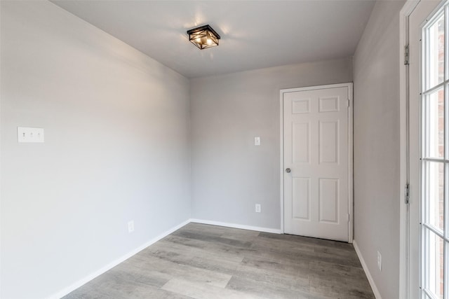 spare room with baseboards and wood finished floors