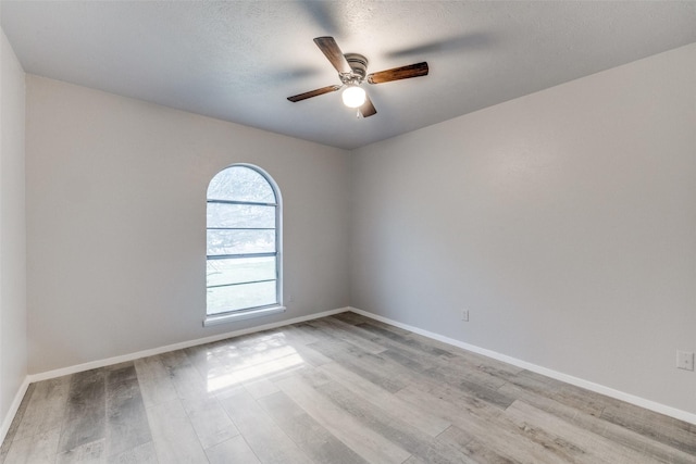 unfurnished room featuring baseboards, a textured ceiling, a ceiling fan, and light wood-style floors