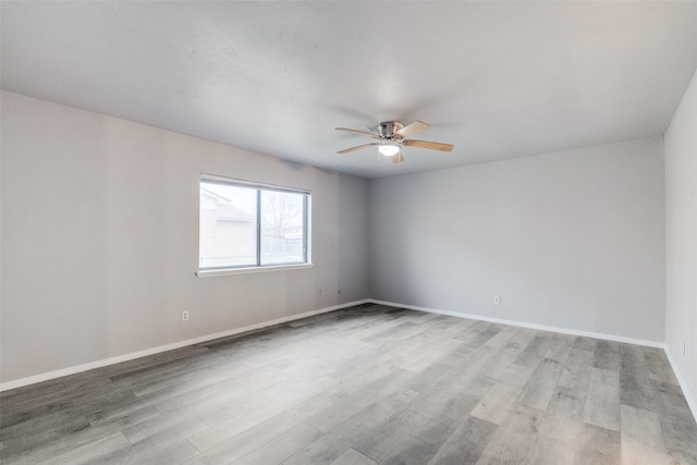 empty room with a ceiling fan, light wood-type flooring, and baseboards