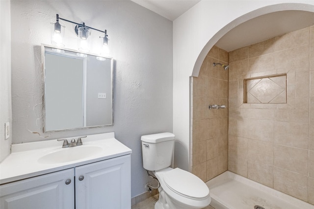 full bathroom with tiled shower, vanity, and toilet