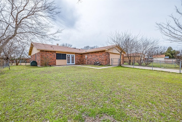 view of front facade featuring an attached garage, brick siding, driveway, french doors, and a front yard