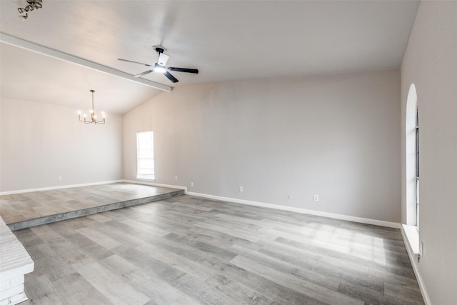 empty room with lofted ceiling with beams, ceiling fan with notable chandelier, light wood-style flooring, and baseboards