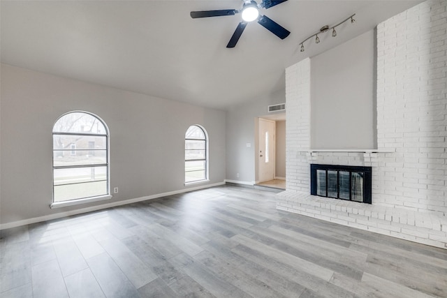 unfurnished living room with a brick fireplace, wood finished floors, visible vents, and baseboards