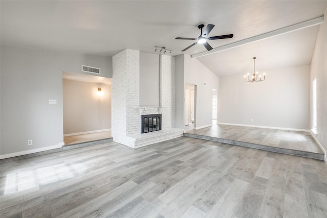 unfurnished living room featuring lofted ceiling, a fireplace, wood finished floors, visible vents, and baseboards