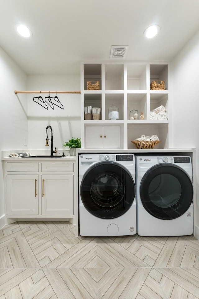 laundry room featuring washer and clothes dryer, recessed lighting, visible vents, cabinet space, and a sink