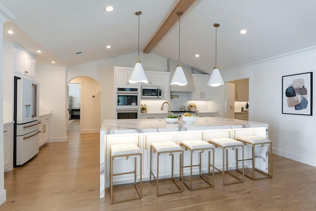 kitchen with white appliances, tasteful backsplash, arched walkways, lofted ceiling with beams, and light wood-type flooring