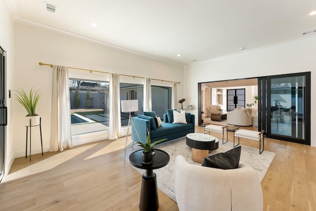 living area featuring ornamental molding, light wood-style flooring, and visible vents